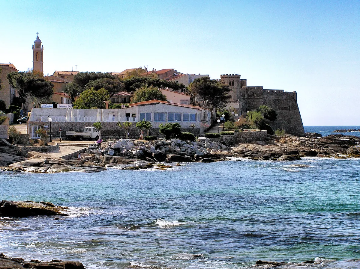 Küstenansicht von Algajola mit Kirche und befestigter Anlage am Meer